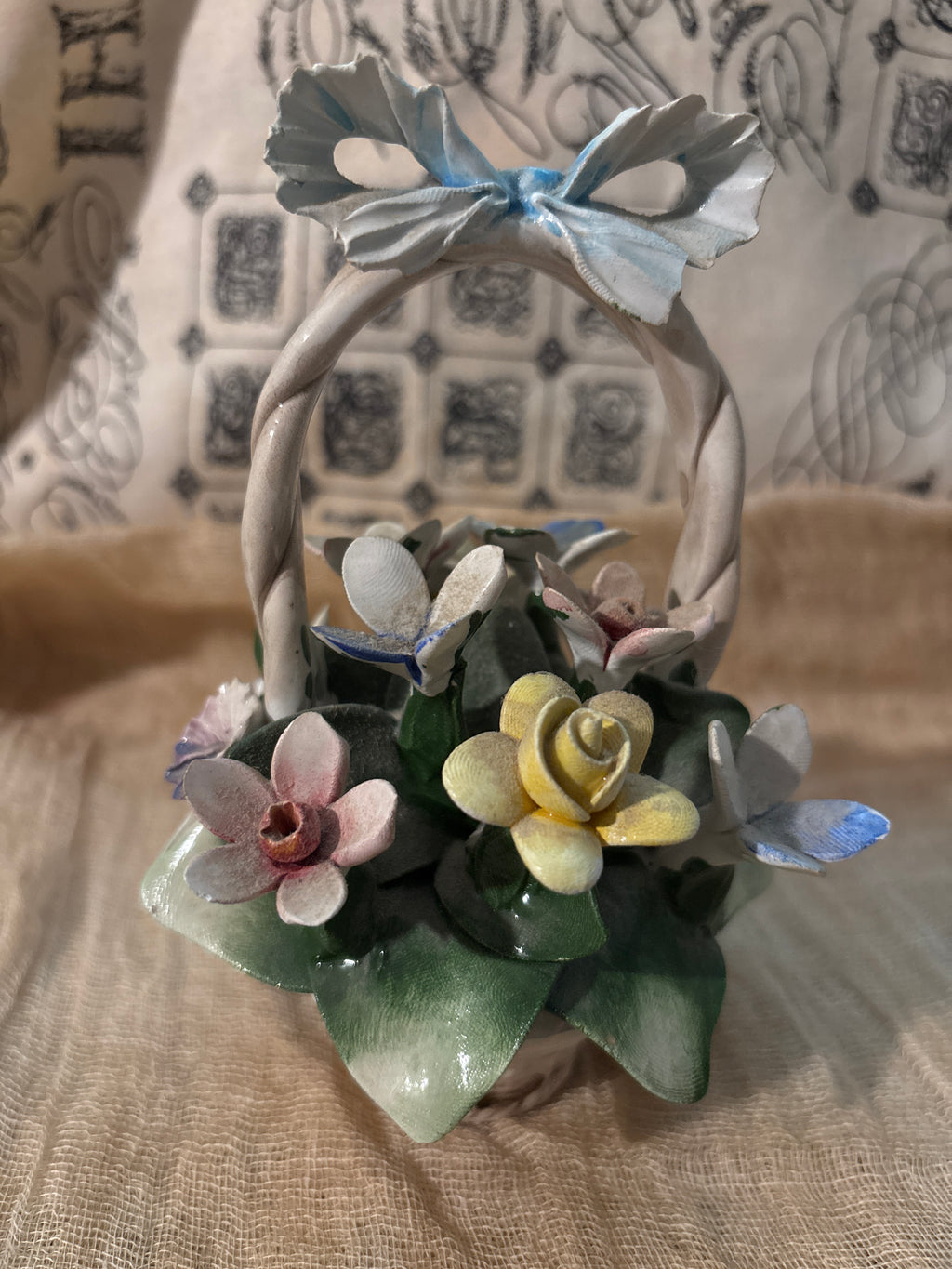 Capodimonte porcelain flower basket made in Italy, featuring a twisted handle topped with a blue bow.